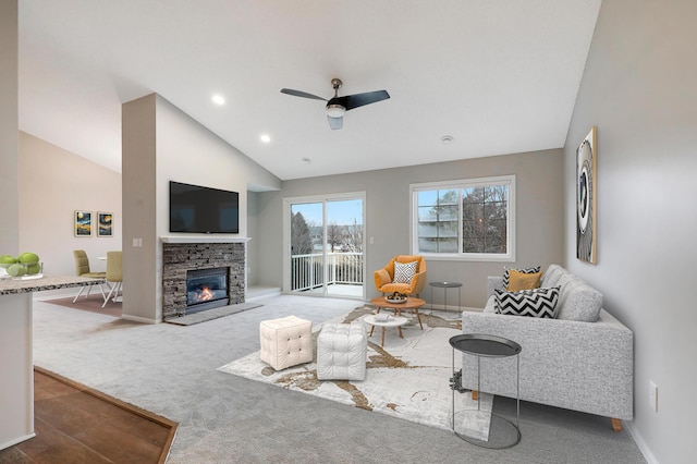 carpeted living area featuring lofted ceiling, a stone fireplace, recessed lighting, a ceiling fan, and baseboards