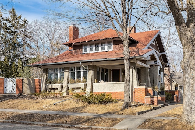 view of front facade featuring a sunroom, a chimney, and brick siding