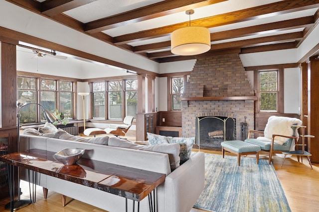 living room featuring a fireplace, wood finished floors, beam ceiling, and a healthy amount of sunlight