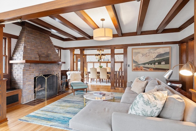 living area with a brick fireplace, beam ceiling, and wood finished floors