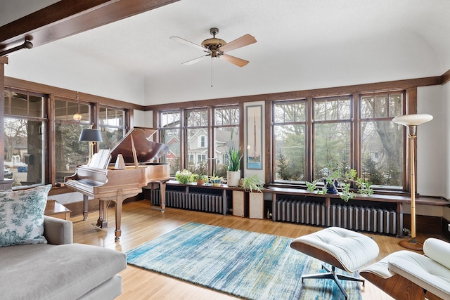 sunroom with ceiling fan, beamed ceiling, and radiator