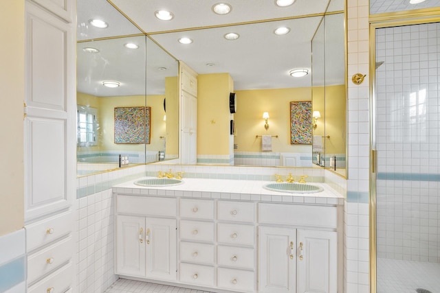 bathroom featuring double vanity, a stall shower, tile walls, and a sink