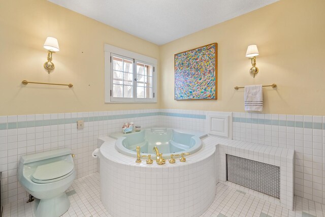 full bath with a wainscoted wall, tile walls, toilet, a jetted tub, and tile patterned floors