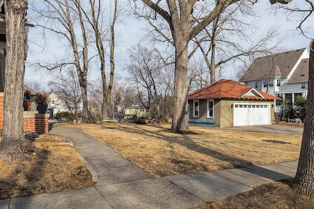 view of yard with an attached garage, a residential view, and concrete driveway