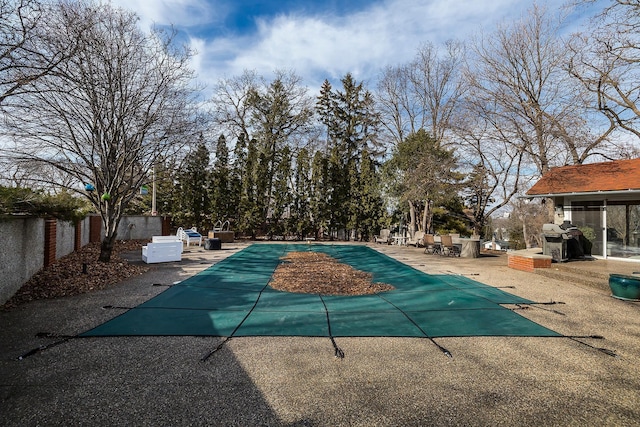 view of pool with a diving board, a patio, and fence