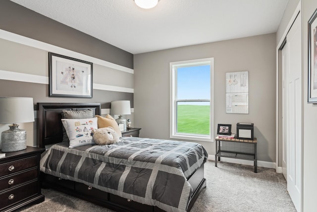 bedroom featuring light colored carpet, a textured ceiling, and baseboards