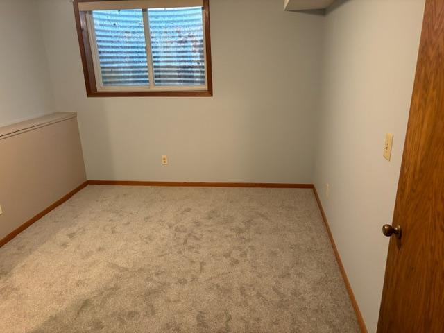 carpeted empty room featuring baseboards