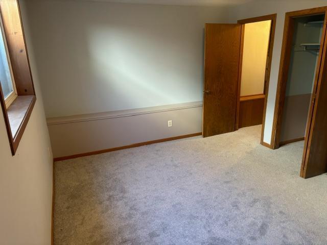 unfurnished bedroom featuring baseboards, a closet, and light colored carpet