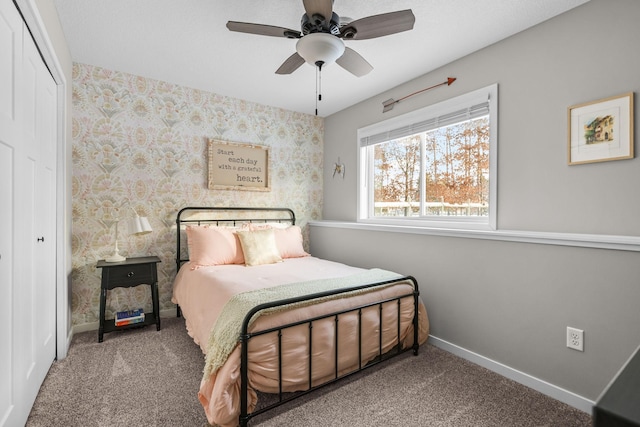 bedroom featuring a closet, carpet floors, a ceiling fan, baseboards, and wallpapered walls