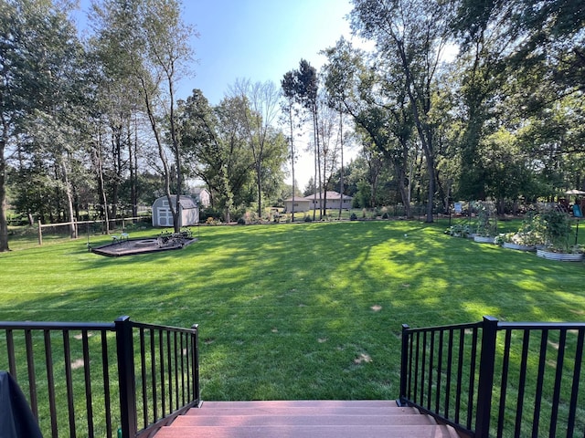 view of yard with an outbuilding, a shed, a garden, a wooden deck, and a fenced backyard