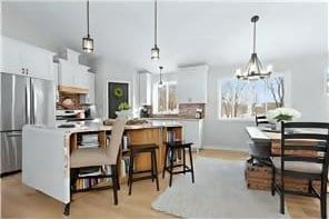 kitchen featuring freestanding refrigerator, white cabinetry, a chandelier, and decorative light fixtures