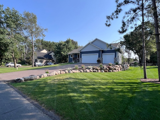view of front of home with a front lawn, stone siding, a garage, and aphalt driveway