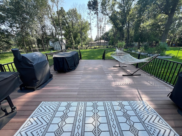 wooden deck featuring a yard, a grill, an outbuilding, and a storage unit
