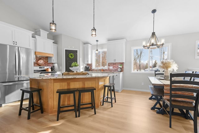 1752 209th Ave NE, East Bethel, MN 55011 - kitchen with appliances with stainless steel finishes, tasteful backsplash, a kitchen island, light wood-type flooring, and vaulted ceiling