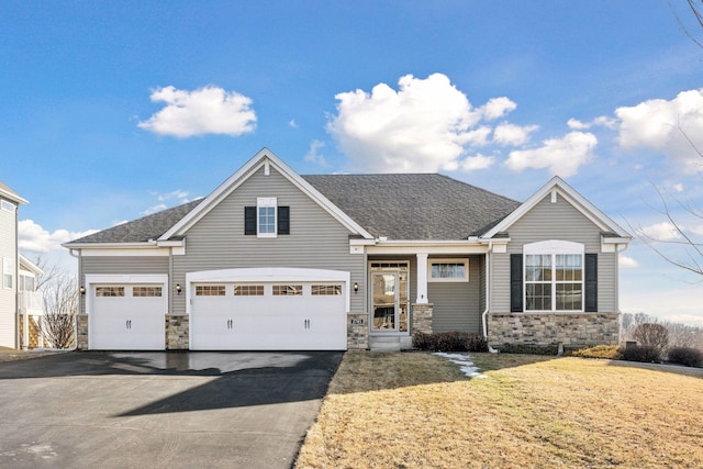 view of front of property featuring stone siding, aphalt driveway, a front lawn, and roof with shingles