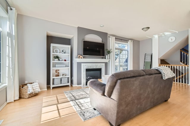 living room featuring a premium fireplace, baseboards, and light wood finished floors