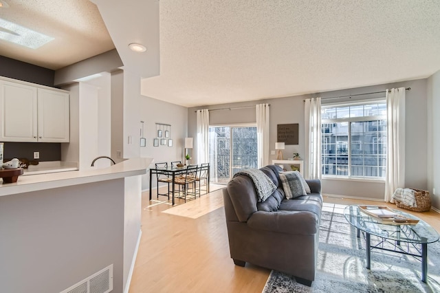 living area featuring baseboards, recessed lighting, a textured ceiling, and light wood-style flooring