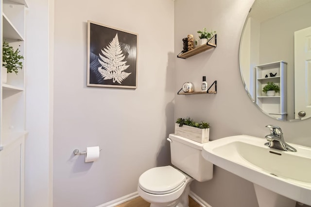 bathroom featuring baseboards, a sink, and toilet