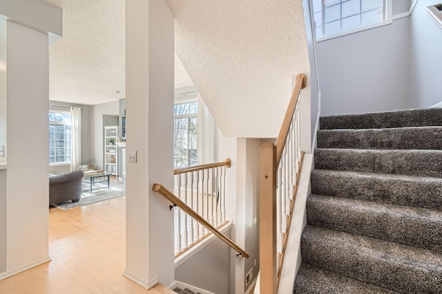 staircase featuring a textured ceiling and wood finished floors