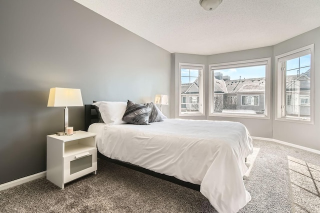 bedroom featuring baseboards, dark carpet, and a textured ceiling