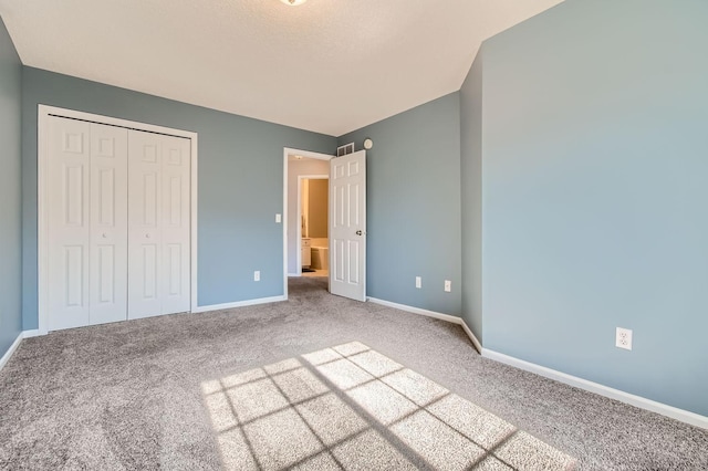 unfurnished bedroom featuring baseboards, carpet, and a closet