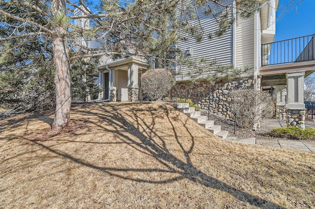 view of home's exterior featuring a balcony and stone siding