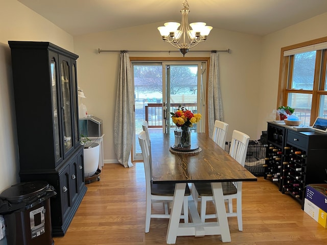 dining room with plenty of natural light, lofted ceiling, a notable chandelier, and light wood finished floors