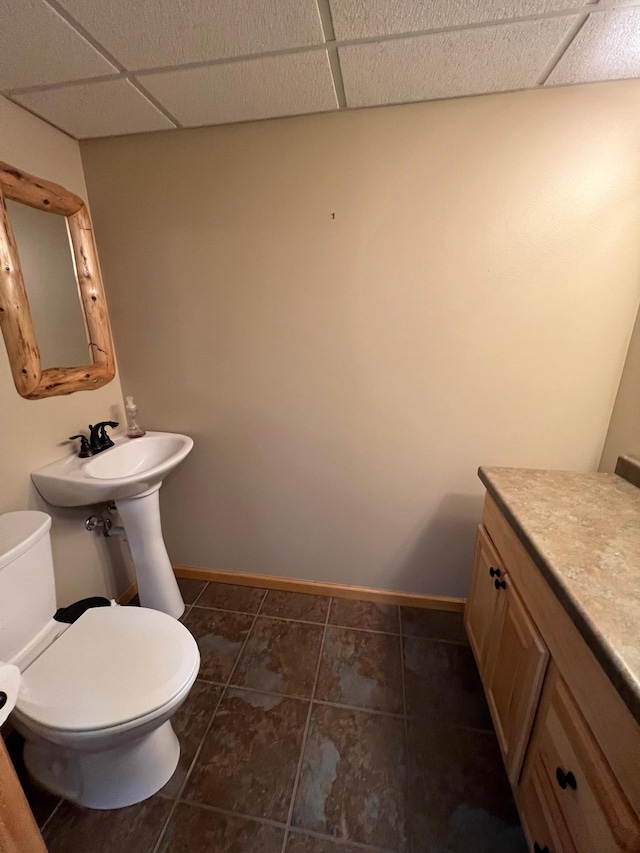 bathroom with toilet, baseboards, a paneled ceiling, and tile patterned floors