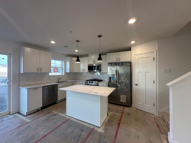 kitchen with a sink, stainless steel appliances, light countertops, white cabinetry, and backsplash