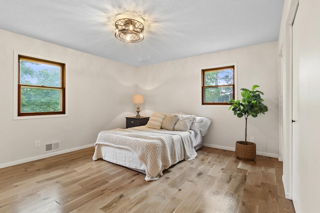 bedroom featuring light wood-style flooring, visible vents, and baseboards