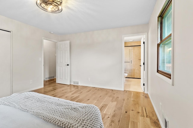 bedroom featuring light wood-style floors, baseboards, visible vents, and connected bathroom