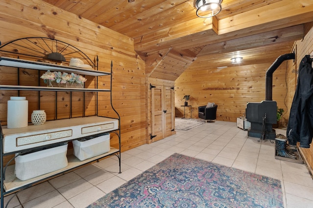 interior space featuring wooden ceiling, wood walls, light tile patterned floors, and a wood stove