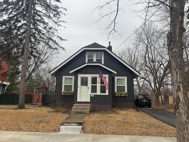 bungalow-style house with driveway, fence, a chimney, and entry steps