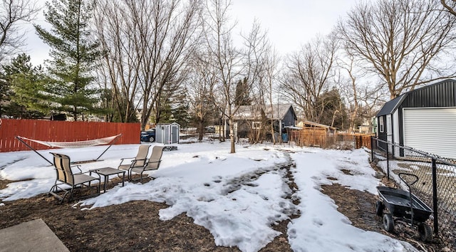 yard covered in snow with an outbuilding, a shed, and fence