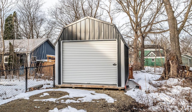 snow covered structure featuring an outdoor structure and fence