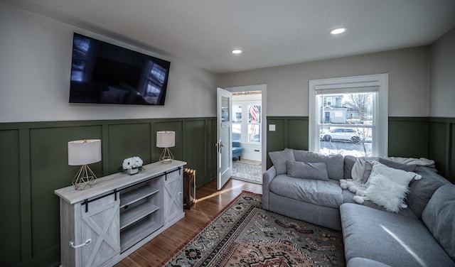 living room with dark wood-style floors, a wainscoted wall, and recessed lighting