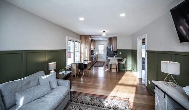 living area featuring recessed lighting, wood finished floors, and a wainscoted wall