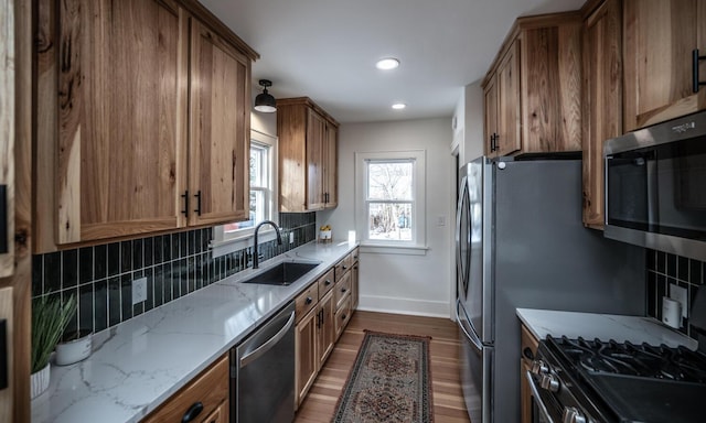 kitchen featuring a sink, light stone counters, backsplash, dark wood-style floors, and appliances with stainless steel finishes