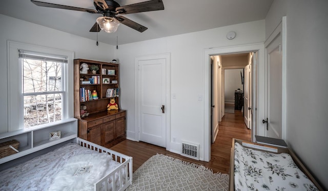 bedroom with visible vents, baseboards, wood finished floors, and a ceiling fan