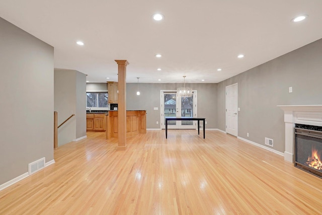 unfurnished living room with recessed lighting, visible vents, a glass covered fireplace, and light wood-style floors