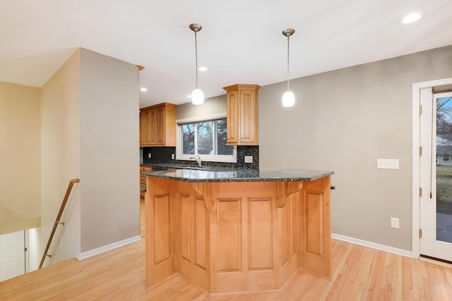 kitchen with a breakfast bar area, backsplash, a sink, baseboards, and light wood finished floors