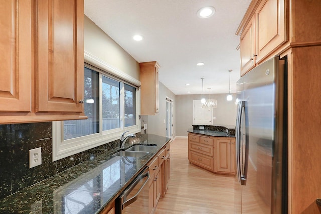 kitchen with recessed lighting, dark stone counters, a sink, light wood finished floors, and appliances with stainless steel finishes