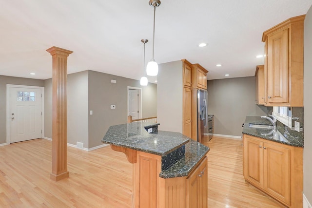 kitchen with baseboards, light wood-style floors, a kitchen breakfast bar, ornate columns, and stainless steel refrigerator with ice dispenser