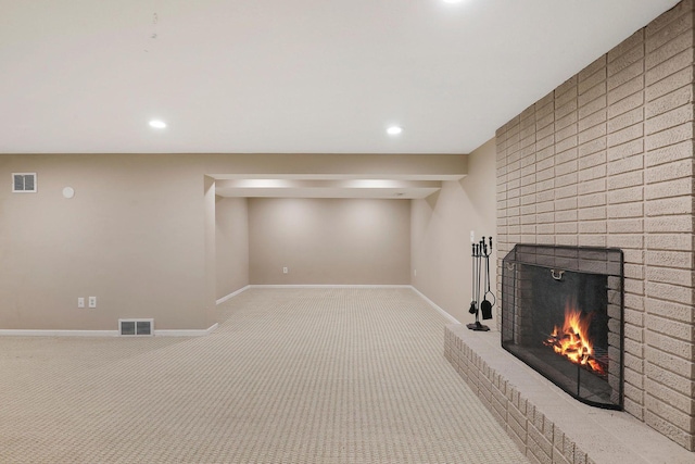 finished basement with carpet floors, baseboards, visible vents, and a fireplace