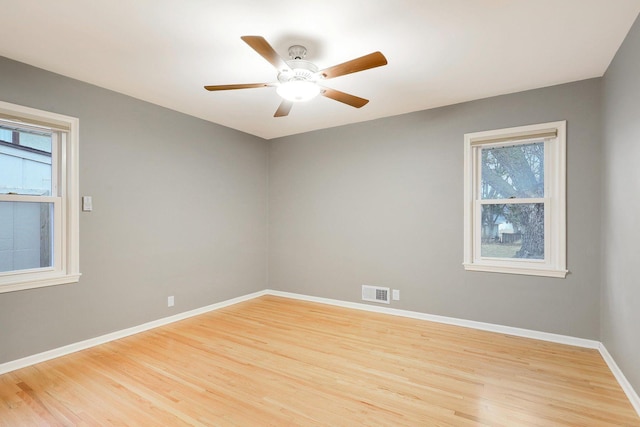 unfurnished room featuring baseboards, a ceiling fan, wood finished floors, and visible vents