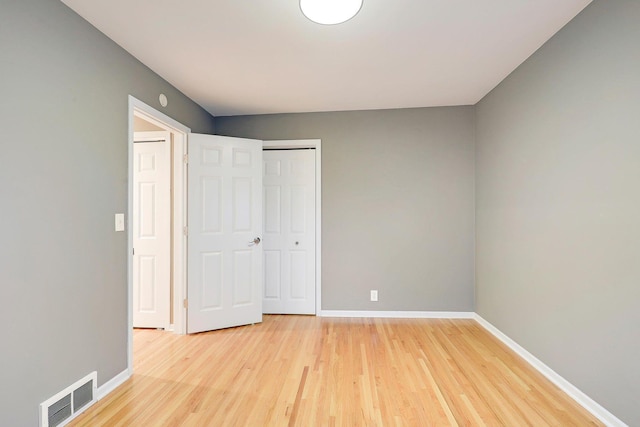 unfurnished bedroom with visible vents, light wood finished floors, baseboards, and a closet