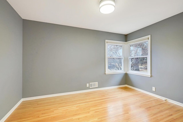 empty room featuring baseboards, visible vents, and light wood-style floors