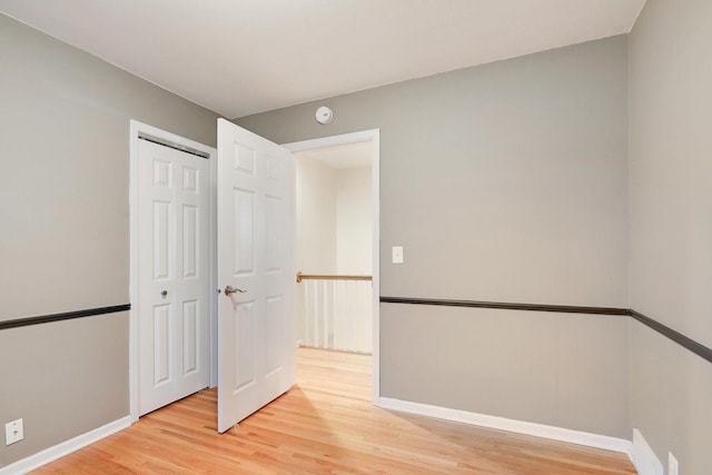 unfurnished bedroom with baseboards, light wood-style flooring, and a closet