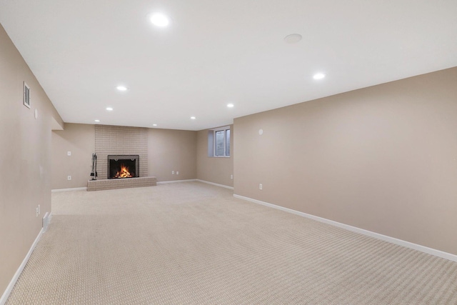 below grade area with visible vents, light carpet, a fireplace, baseboards, and recessed lighting