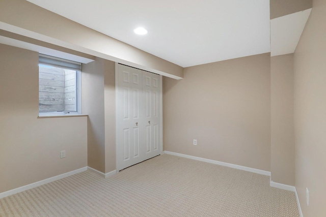 unfurnished bedroom featuring baseboards, a closet, recessed lighting, and light colored carpet